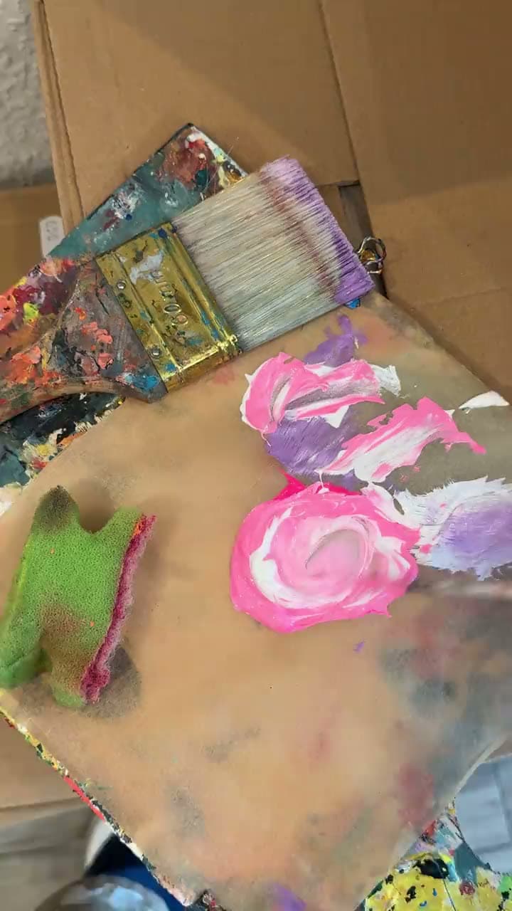 Eine Palette mit rosa Farbe und breitem Pinsel